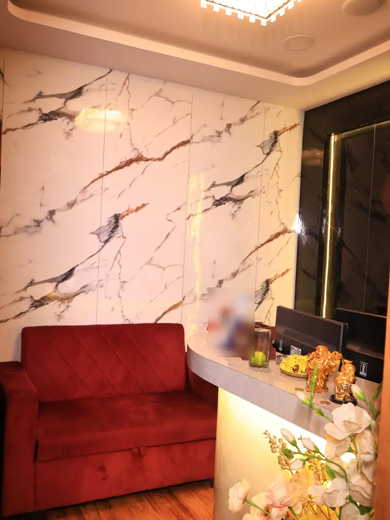 Guest lounge at Amron Spa Juhu with a red velvet sofa beside the reception counter