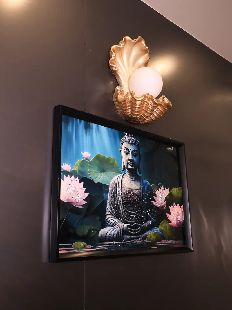Shell-shaped wall lamp above a Buddha and lotus painting in a treatment room